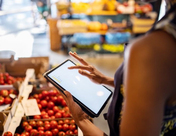 Woman holding an iPad in a grocery store to review a shopping list